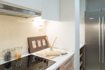 Modern kitchen with induction cooktop, stainless steel refrigerator, and elegant decor