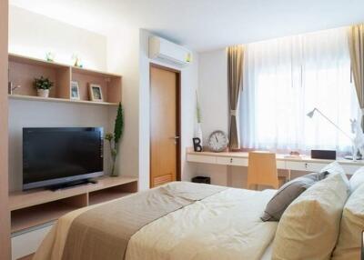 Well-lit bedroom with a bed, TV, desk, and window