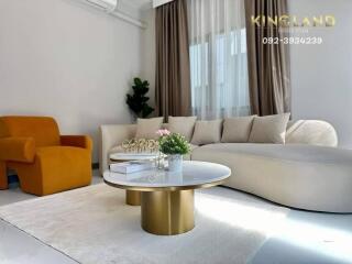 Modern living room with white sofa, orange armchair, and decorative coffee tables