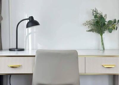 A modern home office desk setup with a lamp and a decorative plant