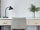 A modern home office desk setup with a lamp and a decorative plant