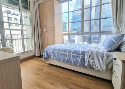 Bright bedroom with wooden flooring and city view