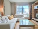 Modern living room with large windows, neutral colors, and entertainment center