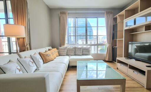 Modern living room with large windows, neutral colors, and entertainment center