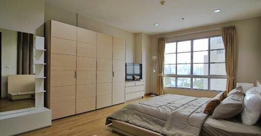 Spacious bedroom with a large window and ample storage