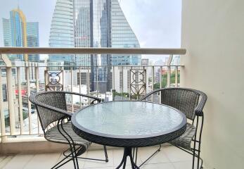 Balcony with a black table and two chairs overlooking cityscape