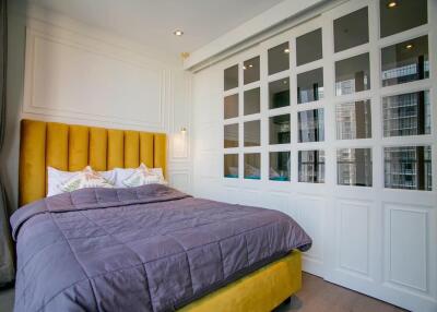 Modern bedroom with yellow headboard, white paneled accent wall and large window