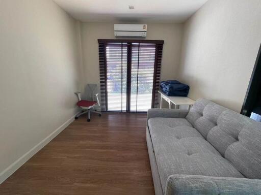 Modern living room with a sofa, chair, and air conditioning