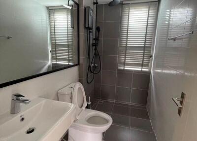 Modern grey-tiled bathroom with sink, toilet, and shower.