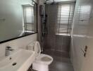 Modern grey-tiled bathroom with sink, toilet, and shower.