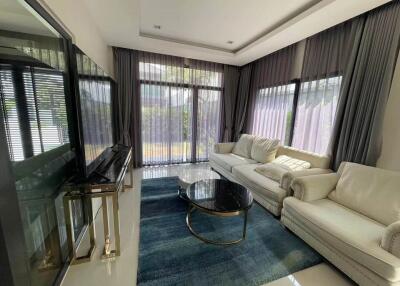 modern living room with large windows, white sofas, and a blue rug