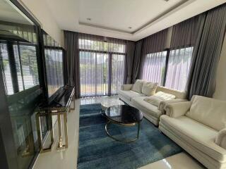 modern living room with large windows, white sofas, and a blue rug