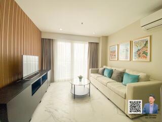 Modern living room with a large TV, a sofa with colorful cushions, and a glass coffee table.