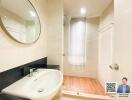 Modern bathroom with sink, round mirror, and shower area.