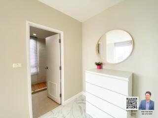 Bright bedroom corner with white dresser and round mirror