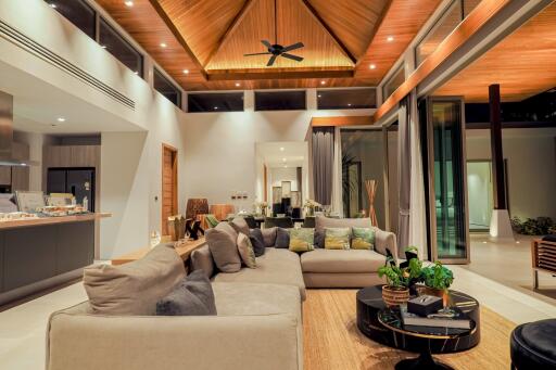 Modern, spacious living room with high wooden ceiling, large L-shaped sofa, glass doors, and contemporary decor