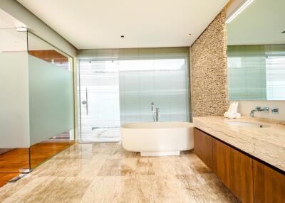 Modern bathroom with a large bathtub, glass shower, and wooden cabinets