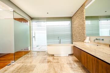 Modern bathroom with a large bathtub, glass shower, and wooden cabinets