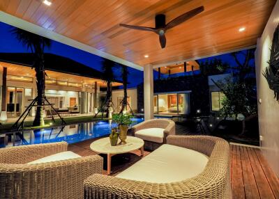 Modern outdoor living space with rattan furniture, ceiling fan, and pool