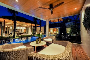 Modern outdoor living space with rattan furniture, ceiling fan, and pool