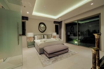 Modern bedroom with a large bed, mirrored table lamps, and a sliding glass door