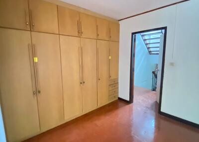 A spacious bedroom with built-in wooden wardrobes and a view of the stairway