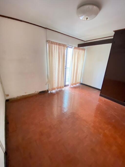 Empty living room with wooden floor and large window with curtains