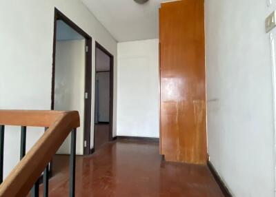 View of an empty hallway with wooden flooring and a simple light fixture