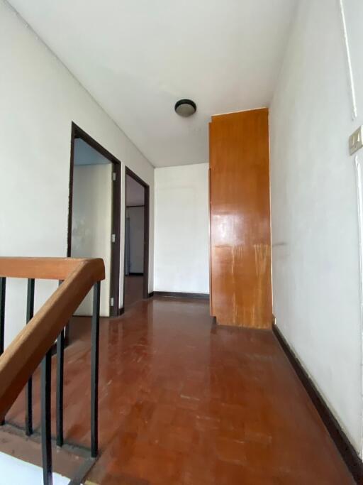 View of an empty hallway with wooden flooring and a simple light fixture