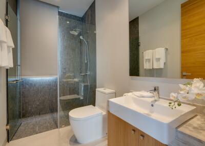 Modern bathroom with glass shower, sink, and toilet