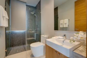 Modern bathroom with glass shower, sink, and toilet