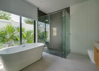 Spacious modern bathroom with glass walk-in shower, freestanding bathtub, and large windows