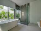 Spacious modern bathroom with glass walk-in shower, freestanding bathtub, and large windows