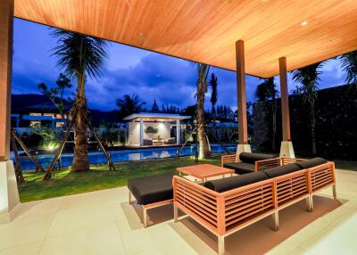 Covered outdoor seating area with pool view at night