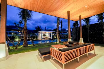 Covered outdoor seating area with pool view at night