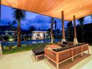 Covered outdoor seating area with pool view at night