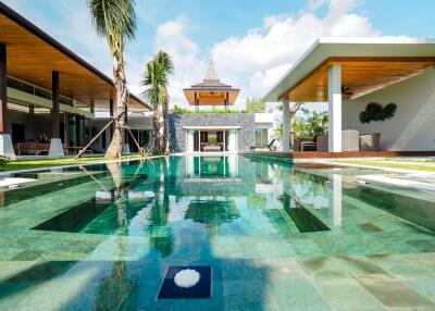 Modern outdoor swimming pool with surrounding patio area and tropical landscaping.