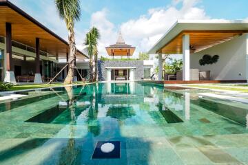 Modern outdoor swimming pool with surrounding patio area and tropical landscaping.