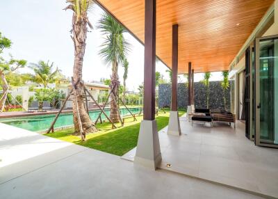 Outdoor patio next to a swimming pool with deck chairs and tropical landscaping