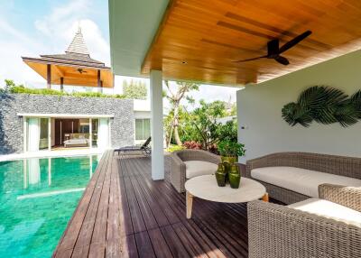 Outdoor living area adjacent to swimming pool with wicker furniture and wooden deck