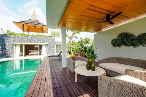 Outdoor living area adjacent to swimming pool with wicker furniture and wooden deck