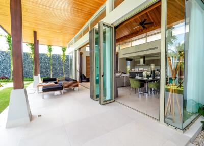 Modern open-plan living and dining area with large glass doors opening to outdoor seating