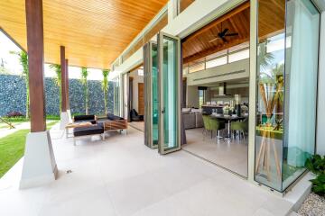 Modern open-plan living and dining area with large glass doors opening to outdoor seating