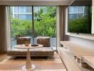 Modern living room with large windows, greenery outside, and minimalist decor