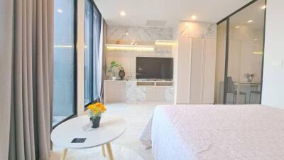 Modern bedroom with large windows, TV, and a decorative table.