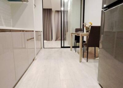 Modern kitchen with dining area featuring sleek cabinets, table and chairs, and a stainless steel refrigerator.