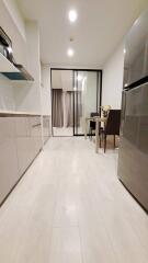 Modern kitchen with dining area featuring sleek cabinets, table and chairs, and a stainless steel refrigerator.