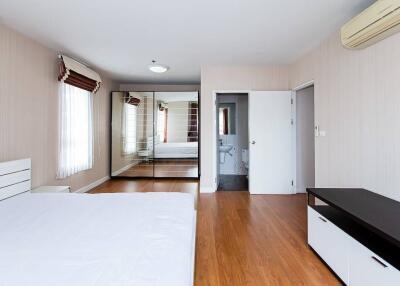 Spacious bedroom with wooden flooring, mirrored wardrobe, and air conditioning