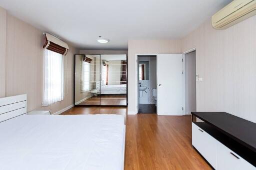 Spacious bedroom with wooden flooring, mirrored wardrobe, and air conditioning