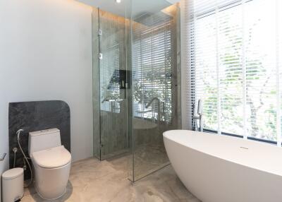 Modern bathroom with freestanding tub, glass shower, and large window